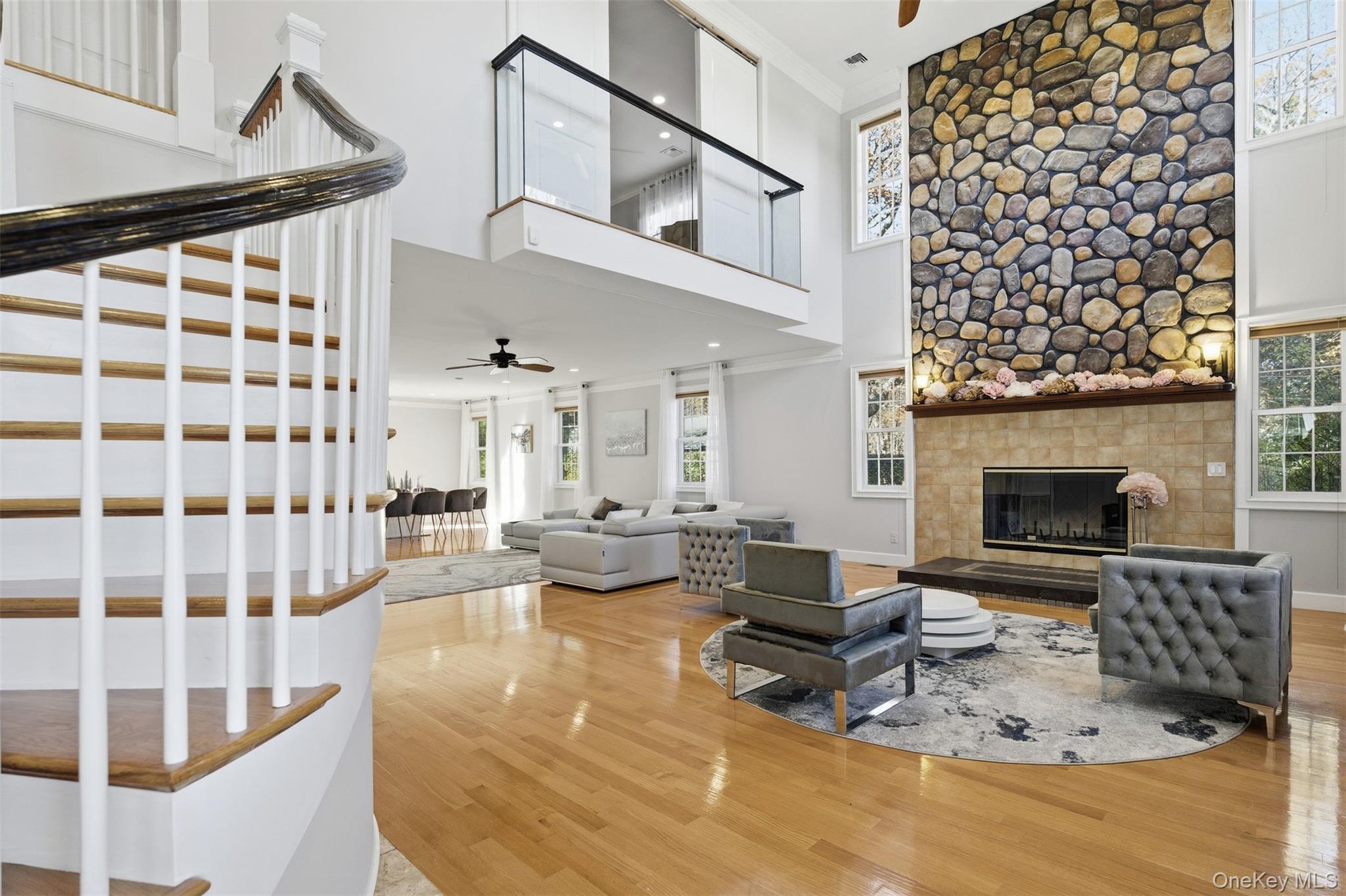 33 A Newtown Road Hampton Bays, NY 11946 - Photo 18 of 50 Living room with a ceiling fan, healthy amount of natural light, crown molding, a towering ceiling, and wood finished floors