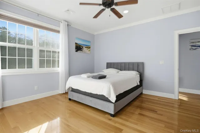 a view of a bedroom with wooden floor and windows