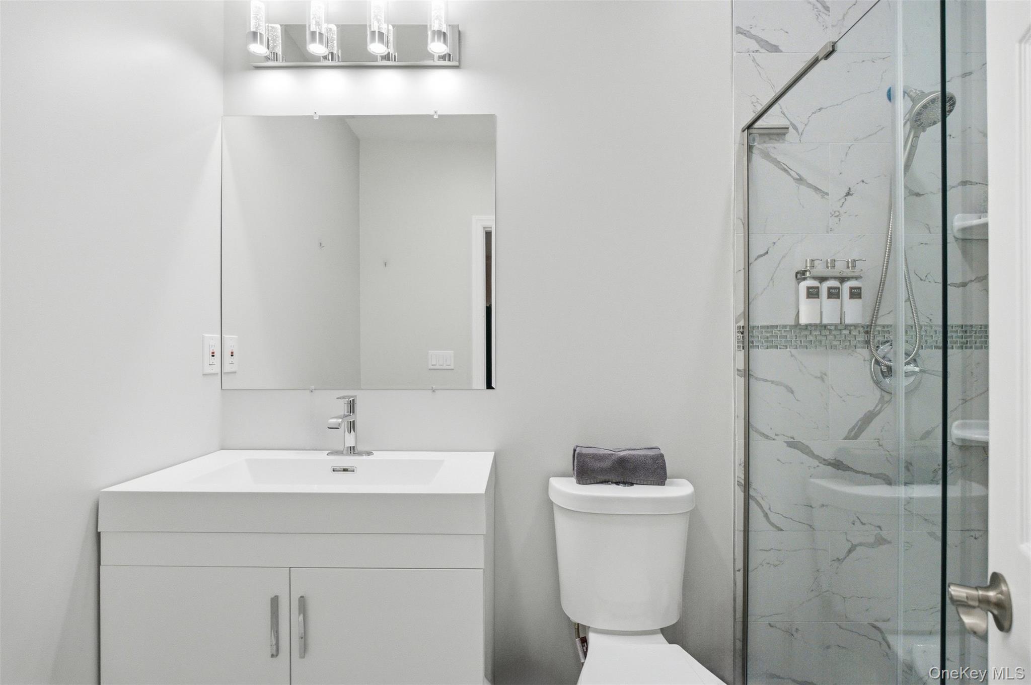 33 A Newtown Road Hampton Bays, NY 11946 - Photo 42 of 50 a bathroom with a sink a toilet and shower