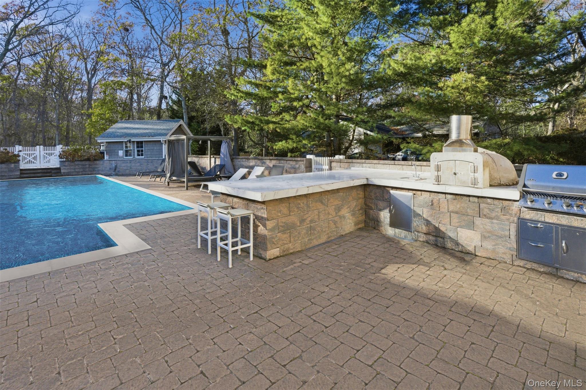33 A Newtown Road Hampton Bays, NY 11946 - Photo 9 of 50 View of pool with a patio, view of wooded area, an outdoor structure, exterior bar, and area for grilling