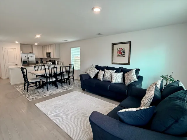 a living room with furniture and a dining table with kitchen view