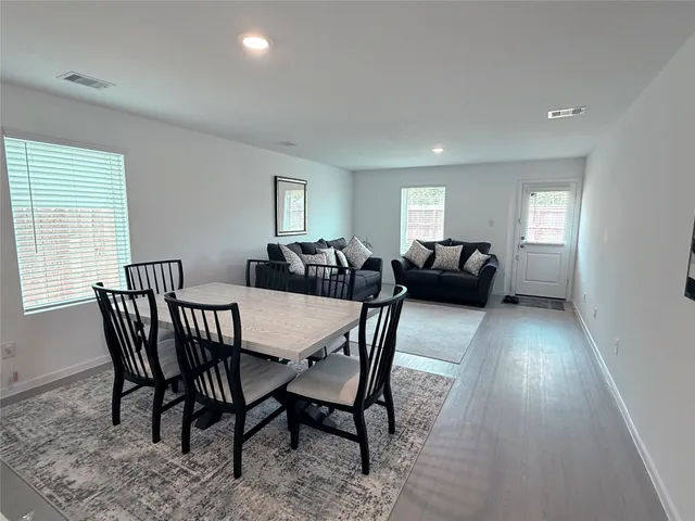 a view of a a dining room with furniture window and wooden floor
