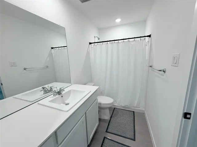 a bathroom with a sink a toilet a mirror and shower