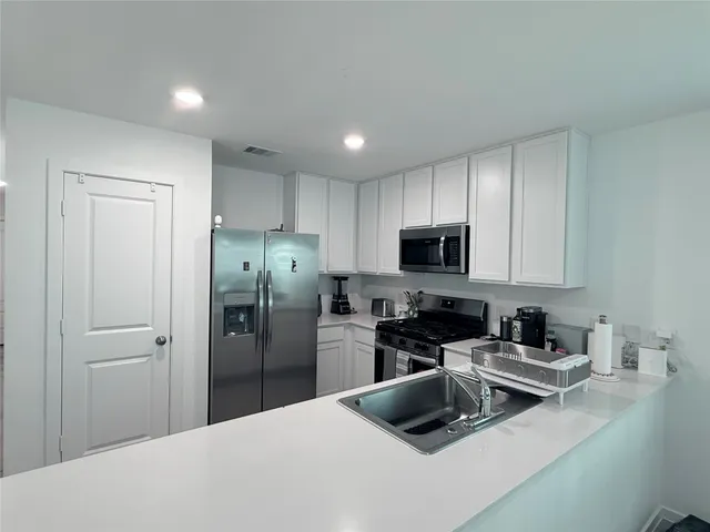 a kitchen with a refrigerator a microwave a sink and cabinets