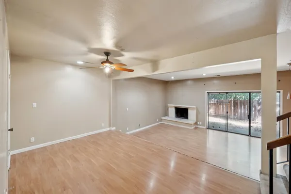 a view of an empty room with a window and wooden floor