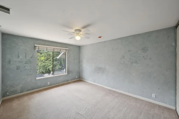 an empty room with a ceiling fan and a window