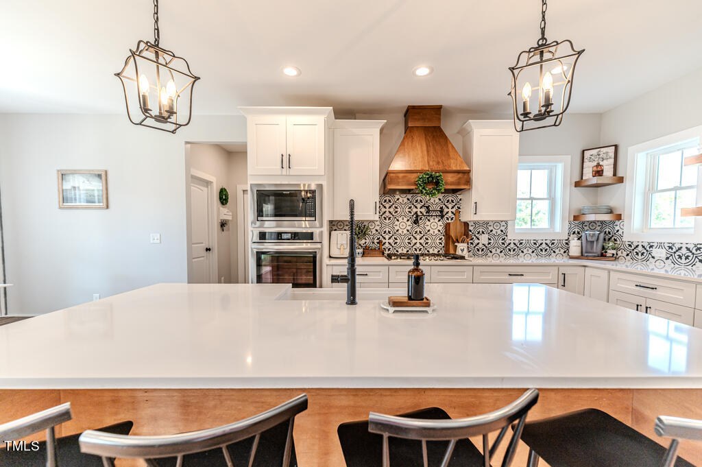 997 Jackson Road Fuquay-Varina, NC 27526 - Photo 25 of 75 a kitchen with stainless steel appliances granite countertop a dining table chairs and chandelier