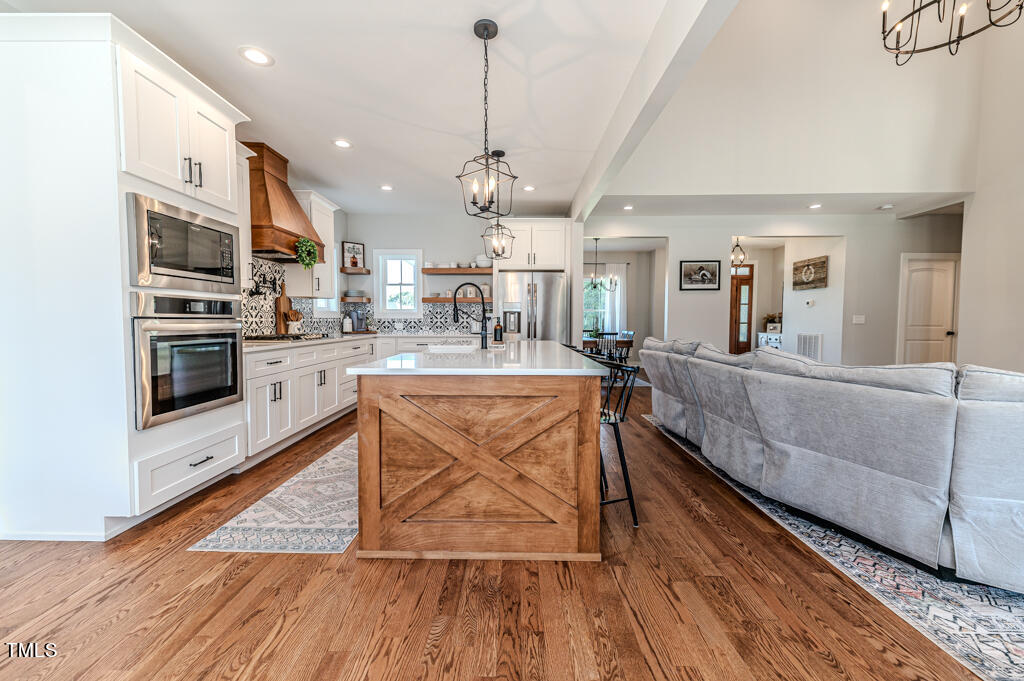 997 Jackson Road Fuquay-Varina, NC 27526 - Photo 32 of 75 a large kitchen with stainless steel appliances granite countertop a stove a sink dishwasher and a dining table with wooden floor