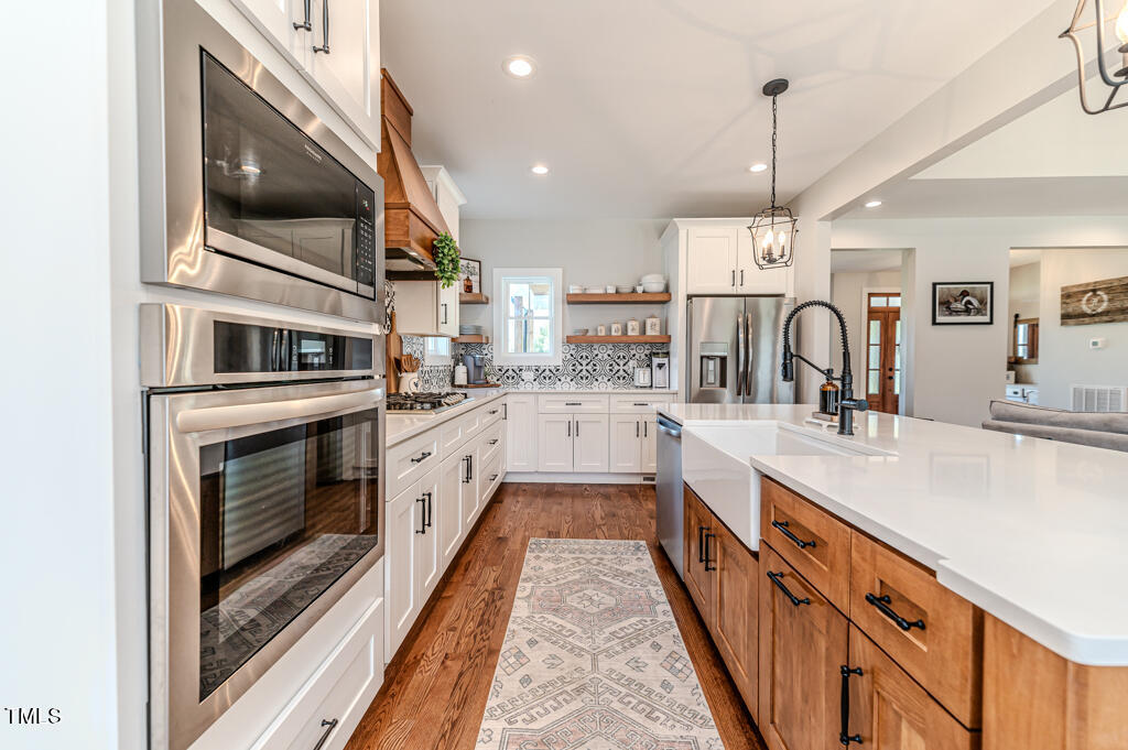 997 Jackson Road Fuquay-Varina, NC 27526 - Photo 74 of 75 a large kitchen with stainless steel appliances kitchen island granite countertop a stove a sink and dishwasher with wooden floor