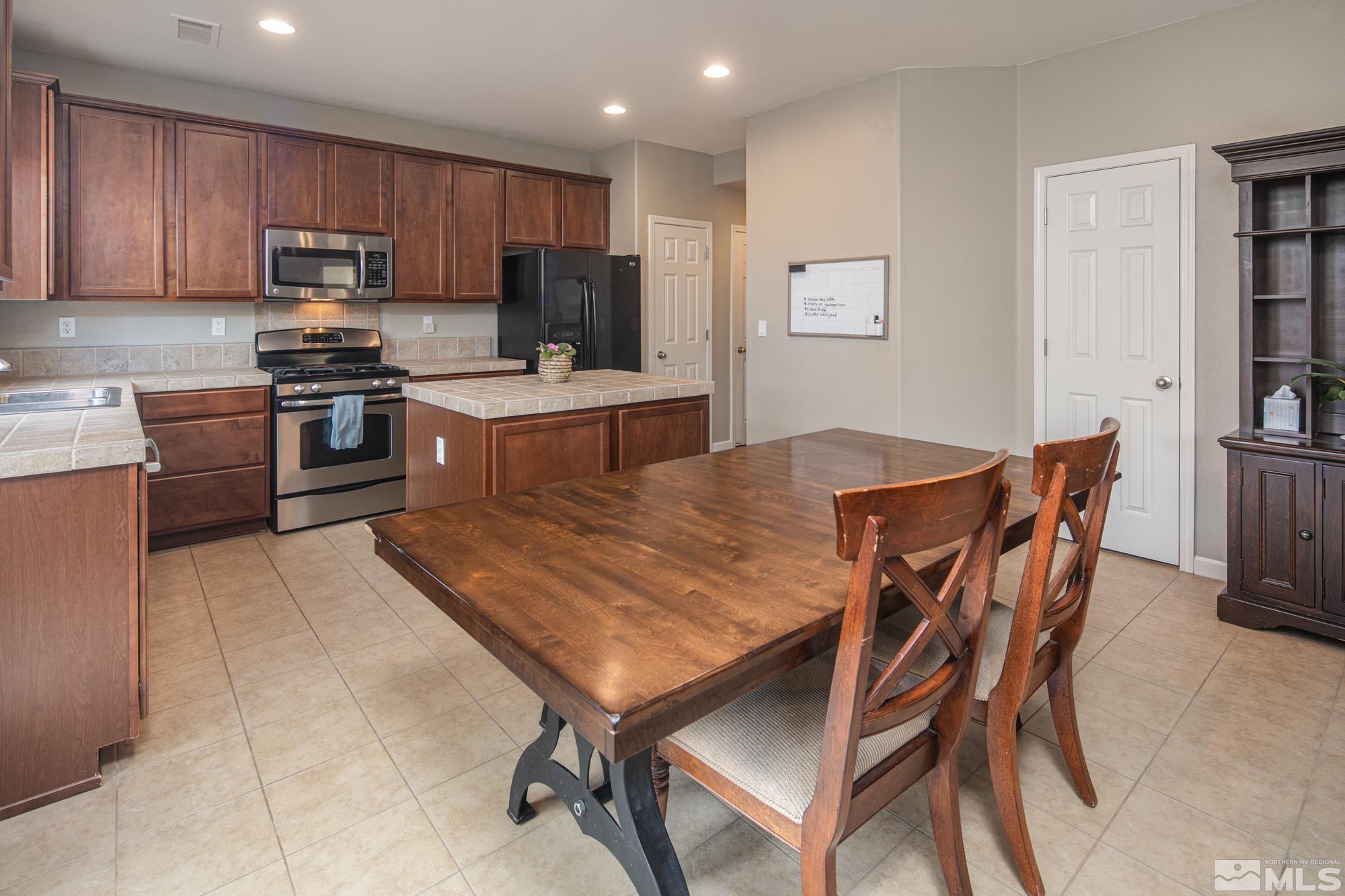 2093 Waterhouse Road Reno, NV 89521 - Photo 9 of 30 a kitchen with granite countertop a stove top oven a sink dishwasher and a refrigerator with wooden floor