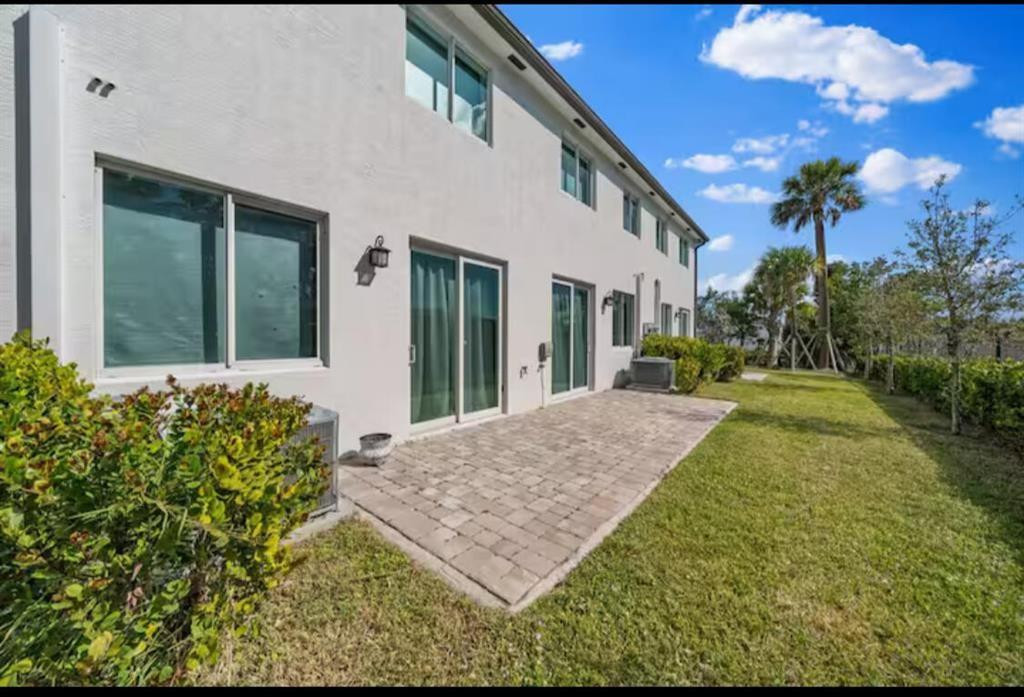 1559 West 26th Court Riviera Beach, FL 33404 - Photo 17 of 17 a view of a white house with a yard and potted plants
