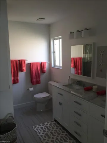 a bathroom with a toilet sink vanity and mirror