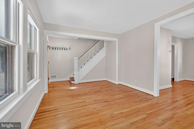 a view of an empty room with wooden floor and stairs