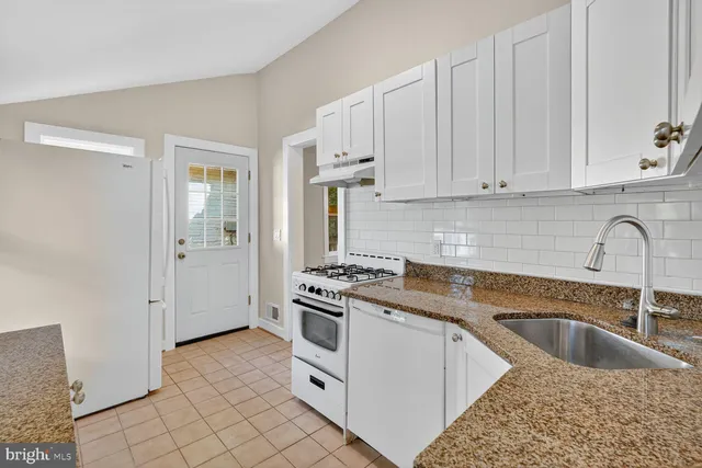 a kitchen with granite countertop a stove sink and cabinets