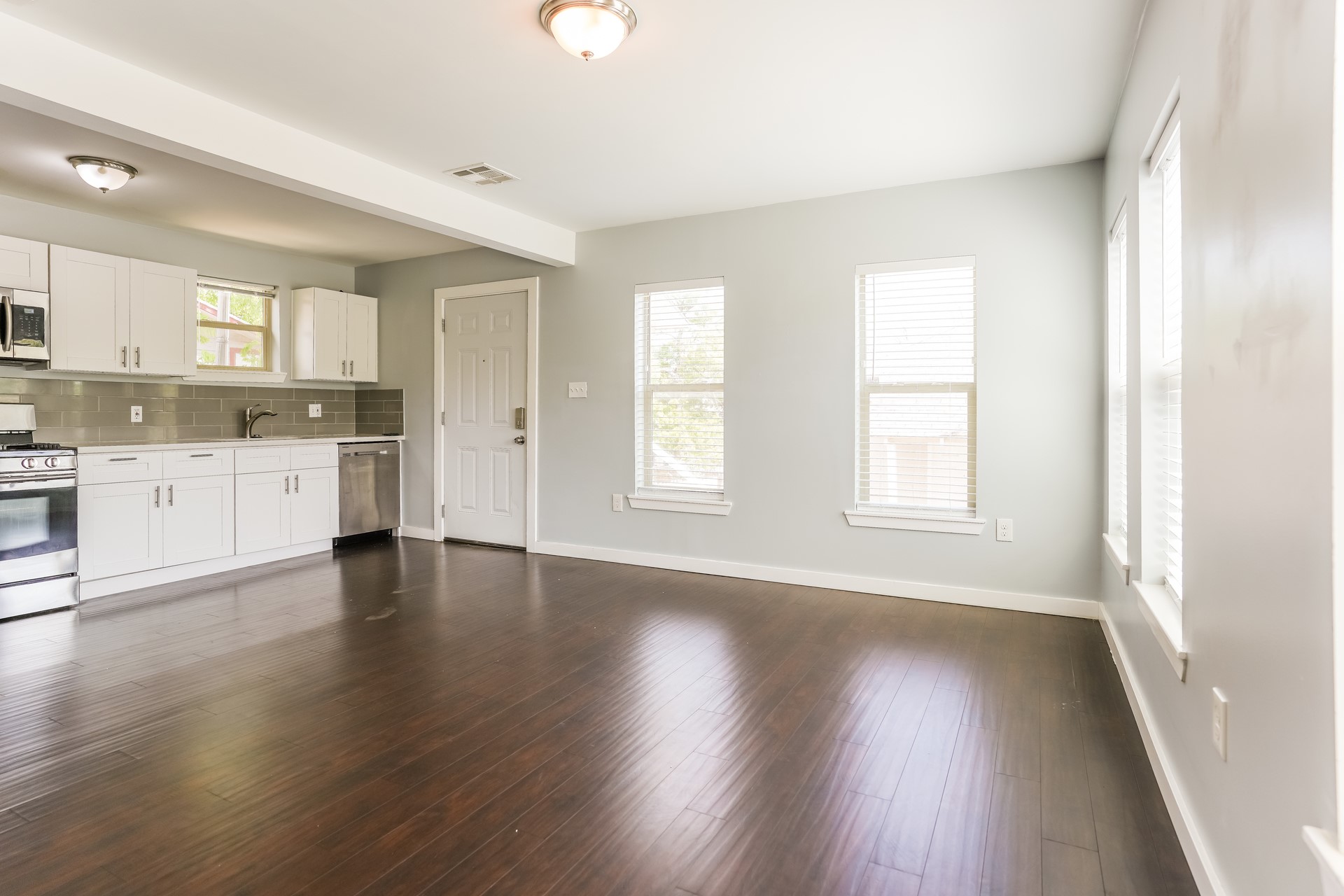 4801 Avenue H Austin, TX 78751 - Photo 14 of 16 Kitchen featuring light countertops, stainless steel appliances, white cabinets, decorative backsplash, and dark wood-style floors