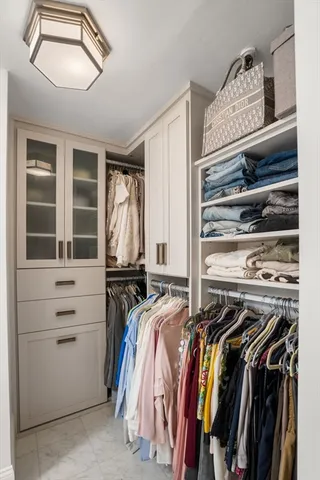 a view of walk in closet with clothes and shoes