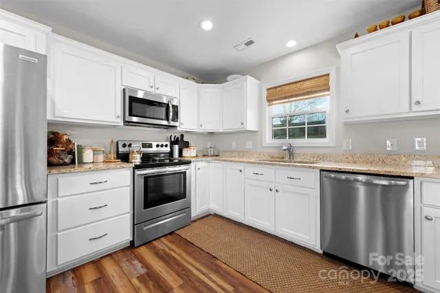 a kitchen with granite countertop white cabinets and stainless steel appliances