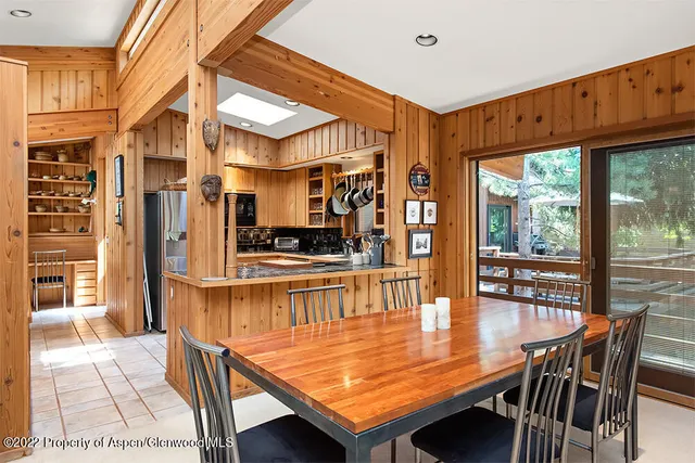 a dining room with stainless steel appliances kitchen island granite countertop a table chairs and a refrigerator