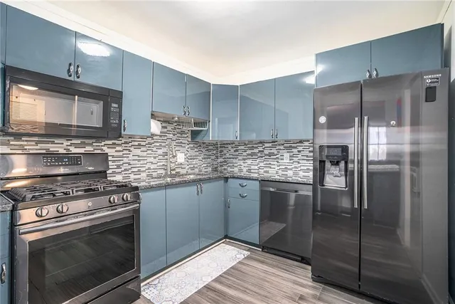 a kitchen with stainless steel appliances granite countertop a stove a refrigerator and a microwave