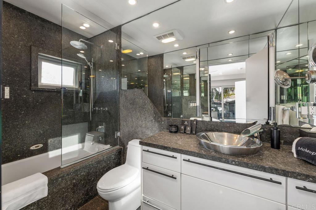 806 4th Street Encinitas, CA 92024 - Photo 31 of 47 a bathroom with a granite countertop sink a toilet a mirror and shower