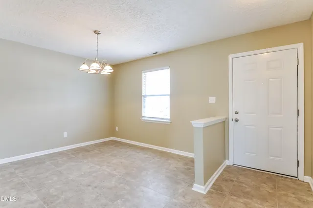 an empty room with a chandelier fan and windows