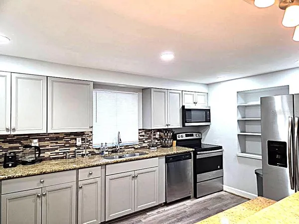 a kitchen with granite countertop a sink a counter top space appliances and cabinets