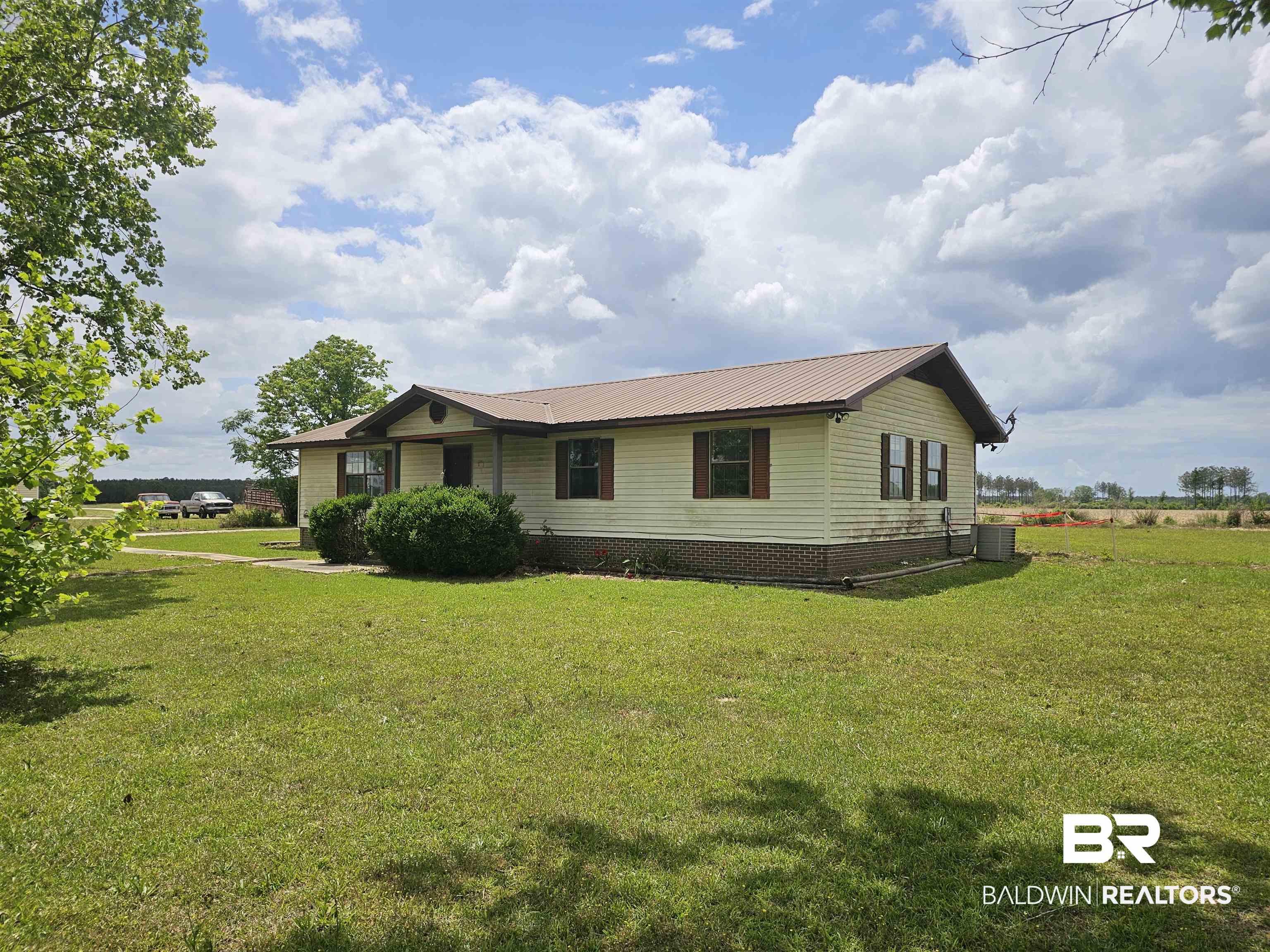 59575 Lottie Road Atmore, AL 36502 - Photo 2 of 23 View of front of property featuring central air condition unit, metal roof, and a front lawn