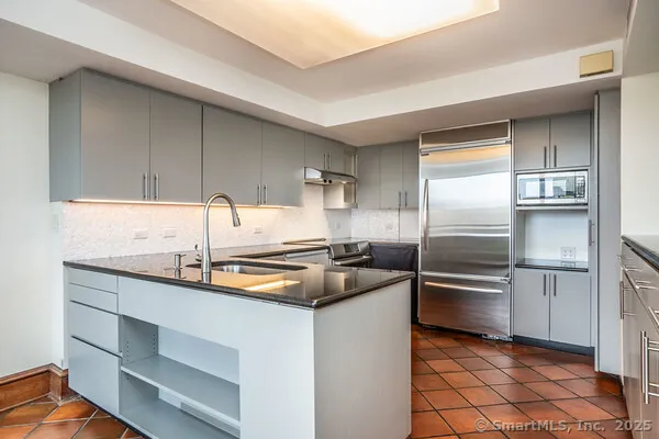 a kitchen with kitchen island a counter top space cabinets and stainless steel appliances