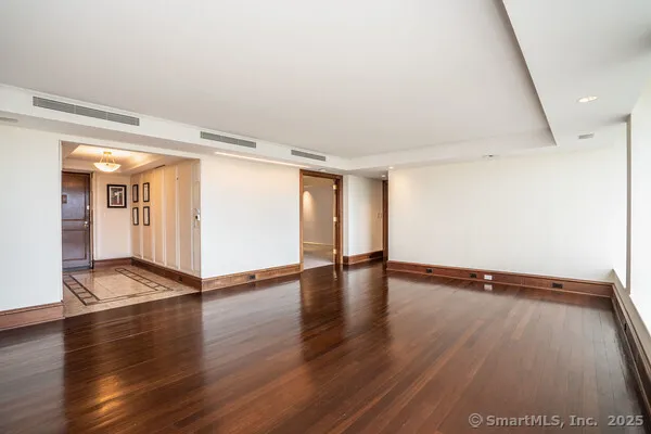 a view of an empty room with wooden floor and a window