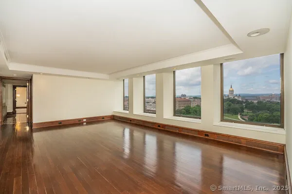 a view of an empty room with wooden floor and a window