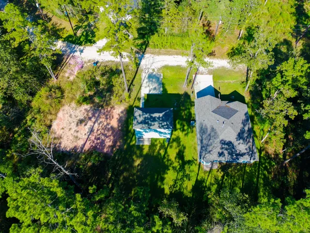 an aerial view of residential house with outdoor space and trees all around