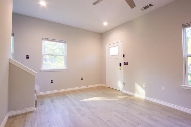 an empty room with wooden floor and windows