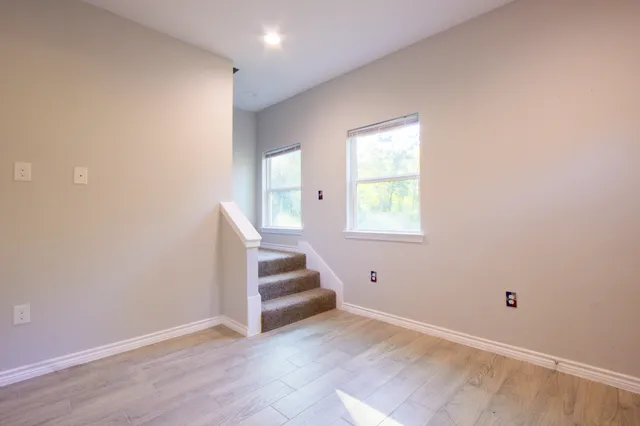 a view of an empty room with stairs and a window