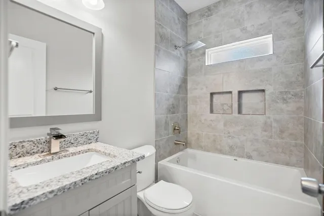 a bathroom with a granite countertop sink toilet mirror and bathtub