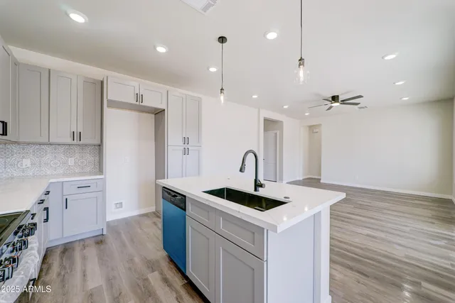 a kitchen that has a lot of cabinets in it with stainless steel appliances granite countertop a sink a stove and a wooden floor