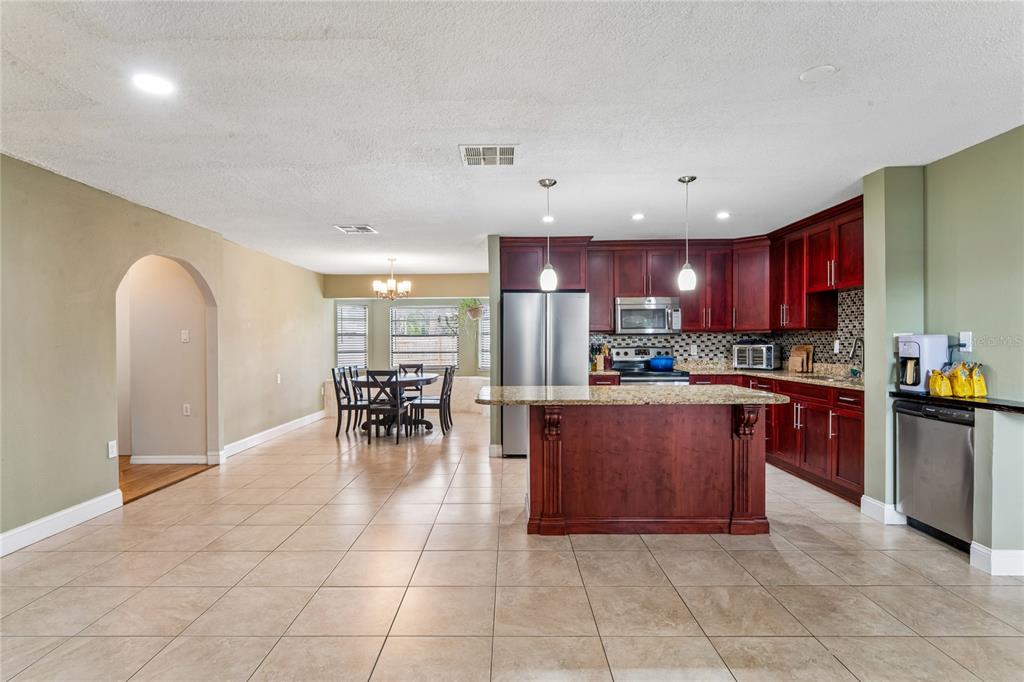 3112 Polk Avenue Spring Hill, FL 34609 - Photo 4 of 50 a kitchen with stainless steel appliances granite countertop a stove top oven a sink dishwasher a dining table and chairs