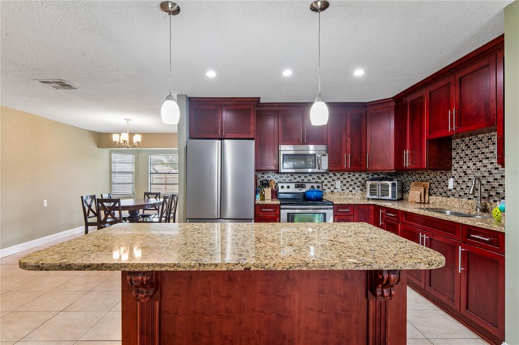 3112 Polk Avenue Spring Hill, FL 34609 - Photo 9 of 50 a kitchen with kitchen island granite countertop a sink a center island stainless steel appliances and cabinets