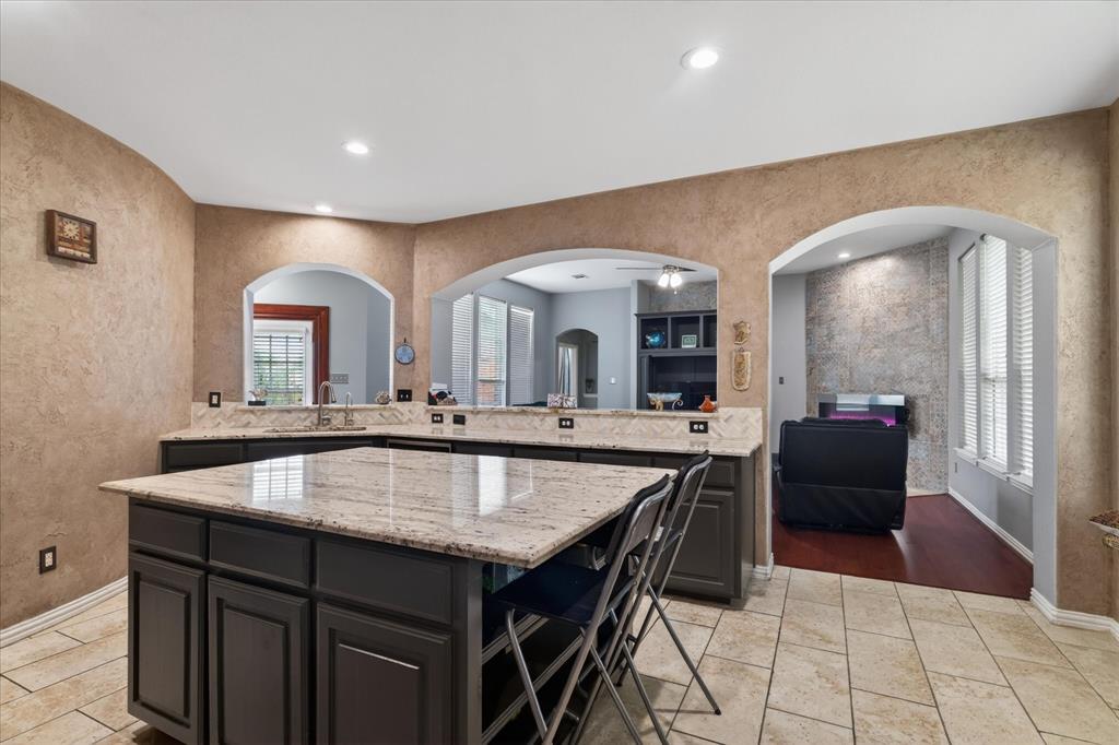 8708 Rugby Road Irving, TX 75063 - Photo 11 of 39 The kitchen features a large island with a granite countertop, dark cabinetry, and tile flooring
