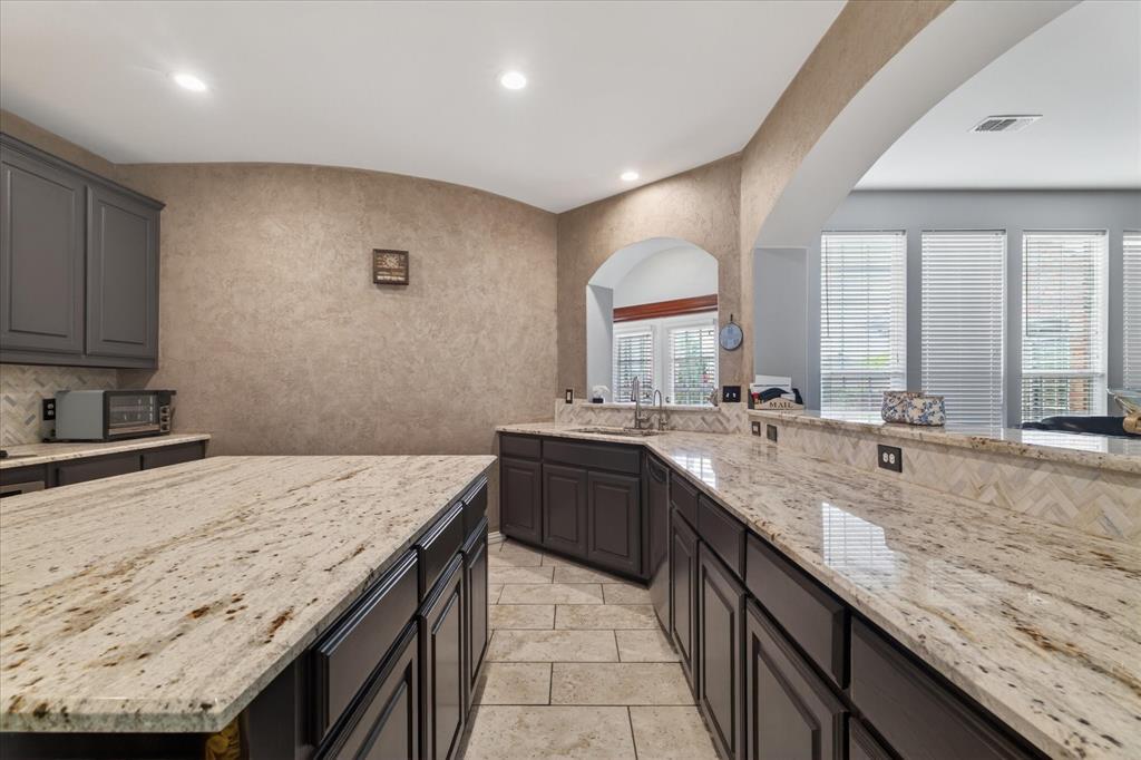 8708 Rugby Road Irving, TX 75063 - Photo 13 of 39 The kitchen features extensive granite countertops, dark cabinetry, and tile flooring