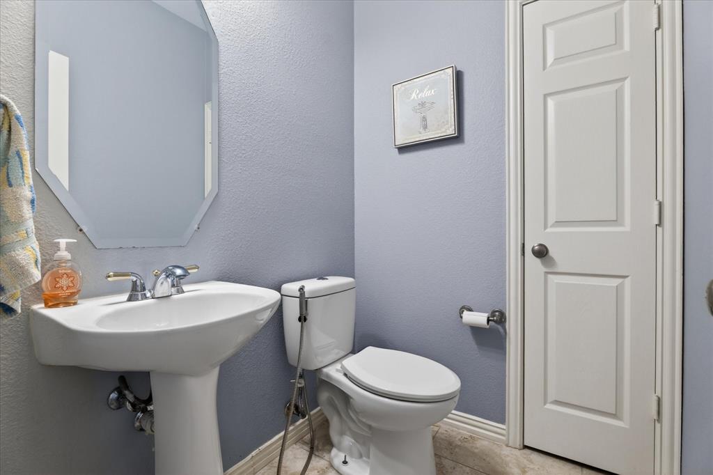 8708 Rugby Road Irving, TX 75063 - Photo 16 of 39 Bathroom with light blue walls, a white pedestal sink with a chrome faucet, and a white toilet
