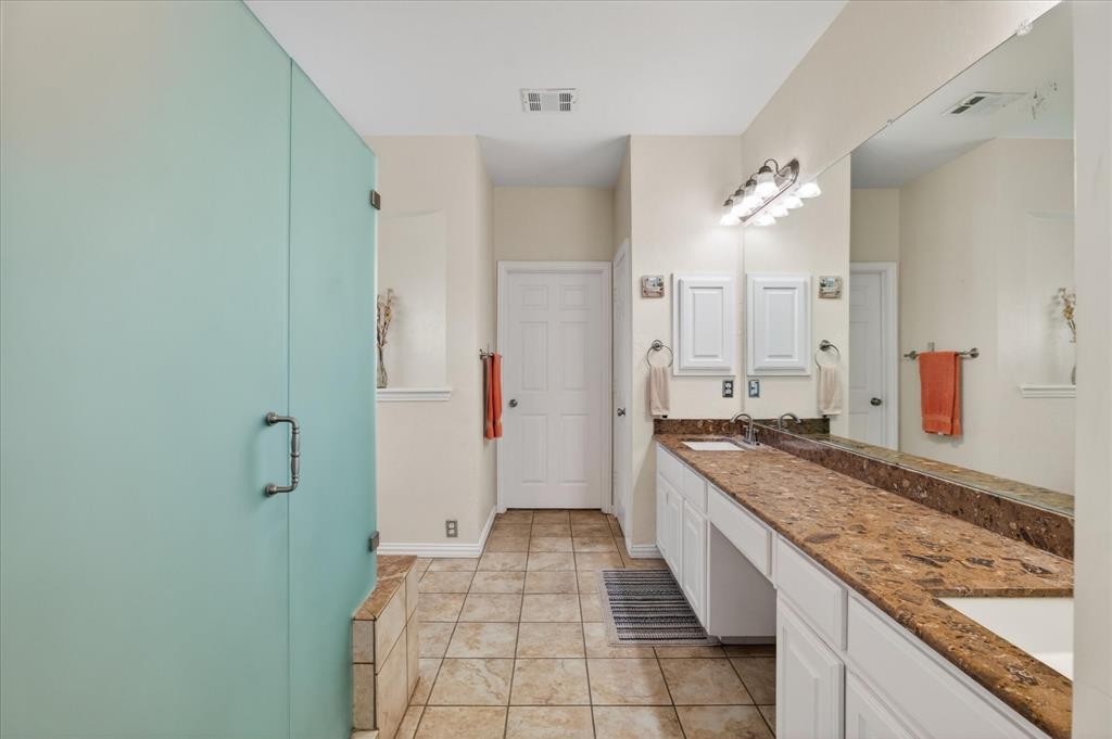 8708 Rugby Road Irving, TX 75063 - Photo 18 of 39 Bathroom featuring a frosted glass shower enclosure, a vanity with a granite countertop, dual sinks, and tile flooring