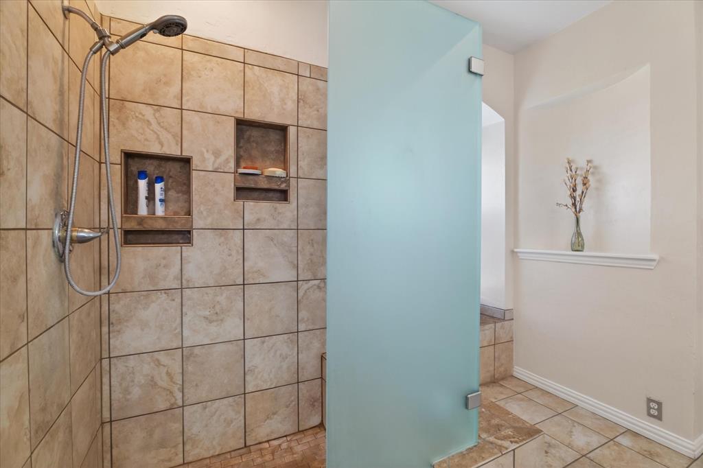 8708 Rugby Road Irving, TX 75063 - Photo 19 of 39 Bathroom featuring a tiled shower with a shower head and built-in niches