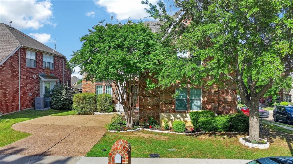 8708 Rugby Road Irving, TX 75063 - Photo 2 of 39 The property features a brick exterior, a paved driveway, and a well-maintained lawn with mature trees and shrubbery