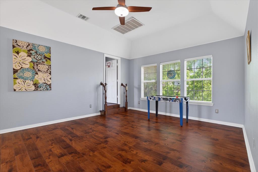 8708 Rugby Road Irving, TX 75063 - Photo 23 of 39 Spacious room featuring hardwood flooring, a ceiling fan, and three windows with blinds