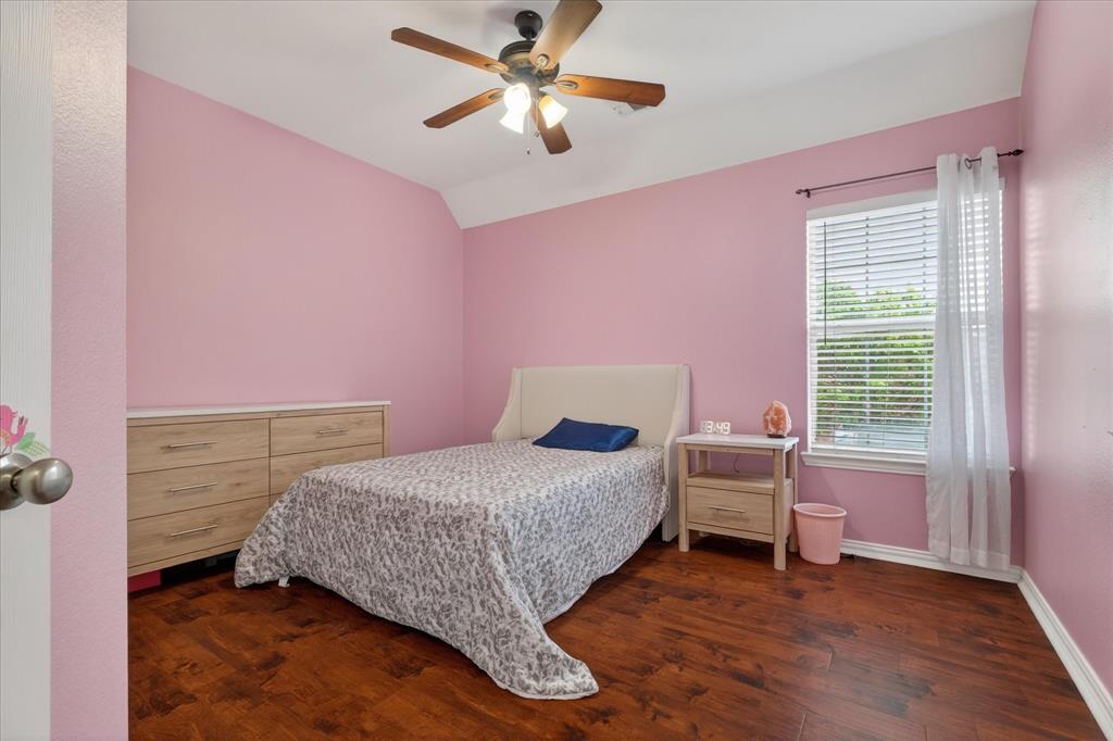 8708 Rugby Road Irving, TX 75063 - Photo 29 of 39 The room features dark wood flooring, a window with blinds and sheer white curtains, and a ceiling fan