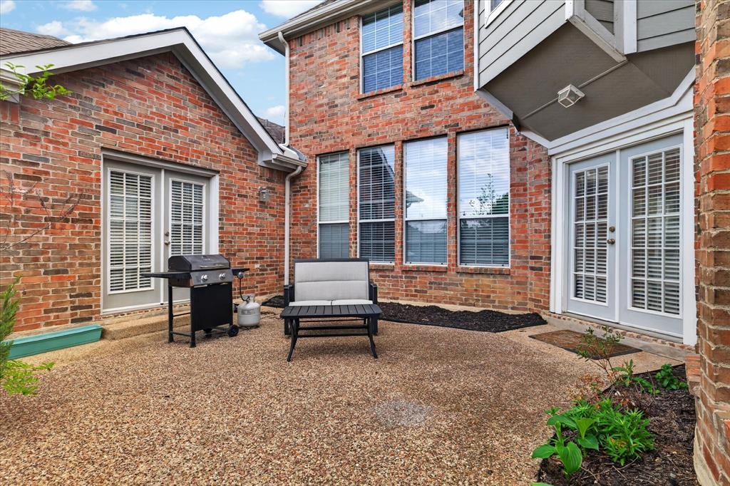 8708 Rugby Road Irving, TX 75063 - Photo 32 of 39 The property features a brick exterior with multiple windows and white-framed double doors providing access to a patio area