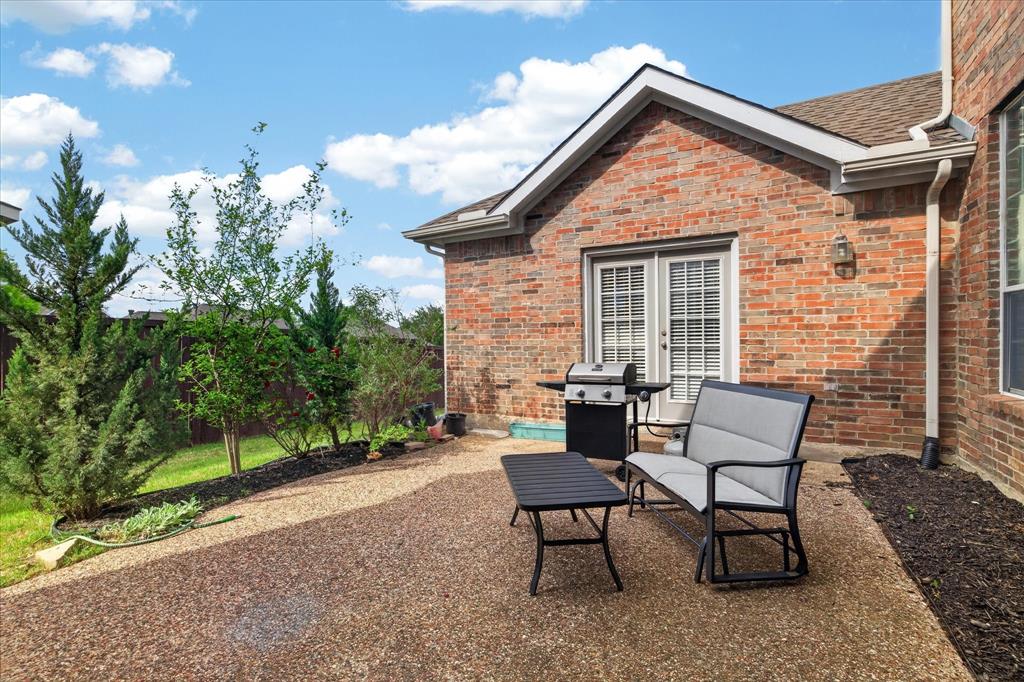 8708 Rugby Road Irving, TX 75063 - Photo 34 of 39 The property features a brick exterior, a gravel patio area, and a green lawn