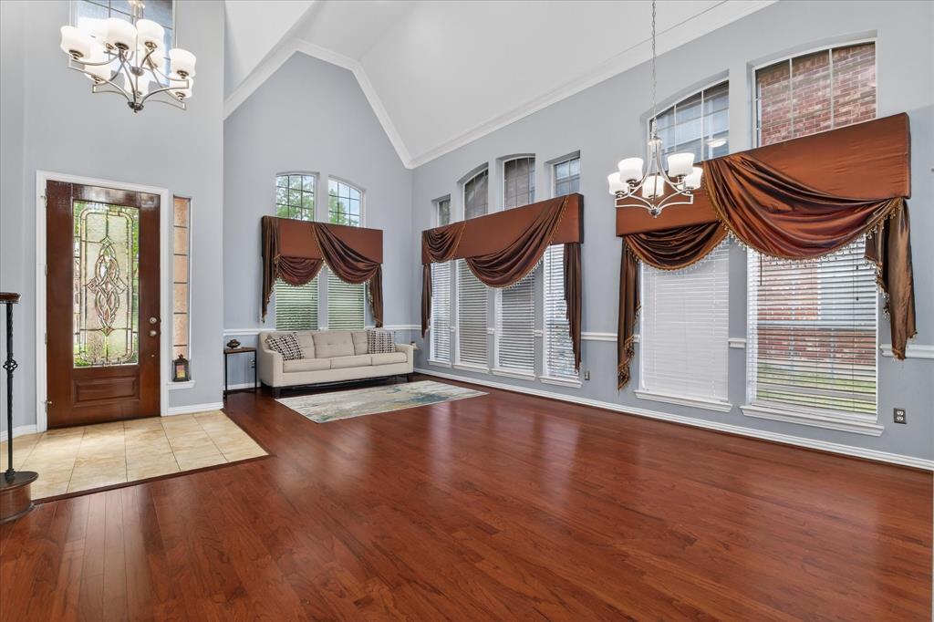 8708 Rugby Road Irving, TX 75063 - Photo 6 of 39 Spacious living area featuring high vaulted ceilings, elegant chandeliers, large windows providing natural light, and lustrous hardwood floors