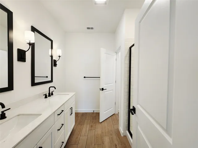 a bathroom with a double vanity sink a mirror and a shower