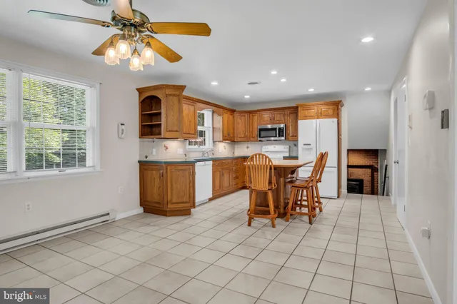 a dining hall with stainless steel appliances granite countertop a stove top oven a sink a dining table and chairs with wooden floor